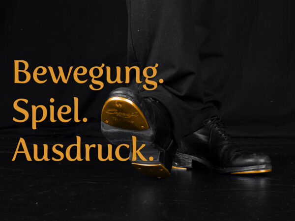(Foto: Johannes Flicker) Nahaufnahme der Füße eines Stepptänzers mit schwarzen Stepptanzschuhen und goldfarbenen Metallplatten an Sohlen und Fersen. Der Hintergrund ist dunkel, sodass die Bewegung der Füße im Mittelpunkt steht. Der goldene Schriftzug "Bewegung. Spiel. Ausdruck." betont die Verbindung von Rhythmus, Präzision und künstlerischem Ausdruck im Stepptanz.